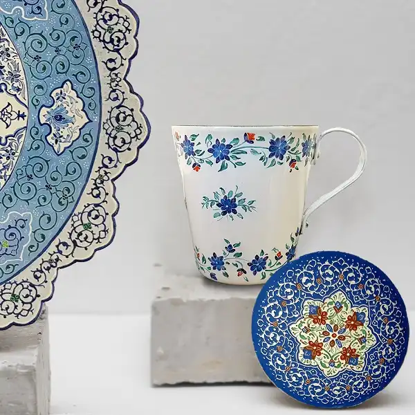 عکس ماگ و بشقاب میناکاری شده با طراحی های سنتی و رنگ های درخشان، نمایانگر اصالت هنر میناکاری ایرانی برای استفاده تزئینی و کاربردی